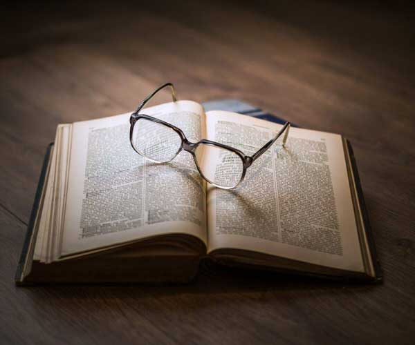 vieux livre ouvert avec lunettes posées dessus